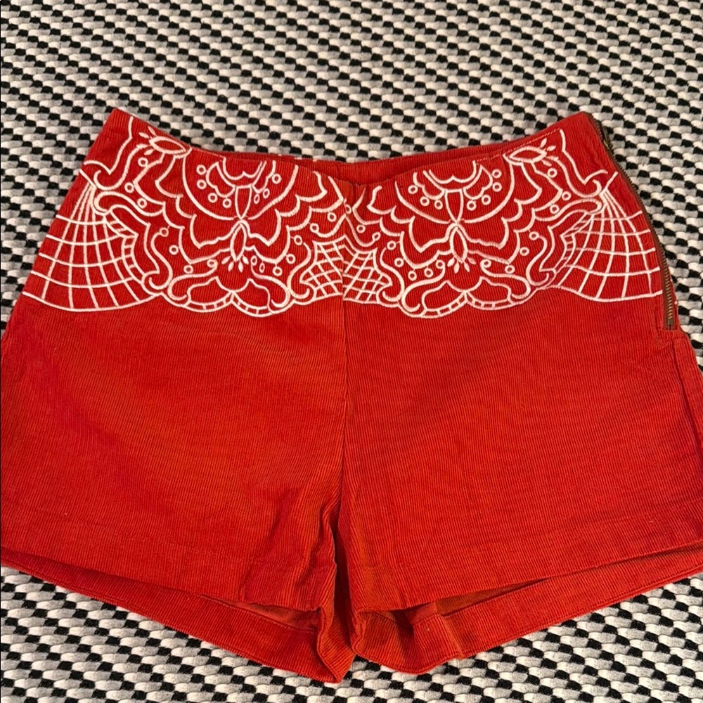 Red corduroy side zip shorts with white stitching design at waist